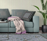 Living room with a teal sofa, patterned cushions, and a plant.