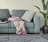 Living room with a teal sofa, patterned cushions, and a plant.