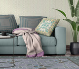 Living room with a teal sofa, floral pillow, and patterned rug.