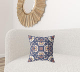 Decorative pillow with floral pattern on a white couch, with a wooden mirror in the background.