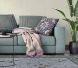 Living room with a teal sofa, floral pillow, and patterned rug.