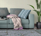 Living room with a teal sofa, patterned rug, and decorative pillows.
