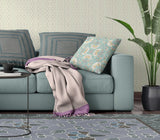 Living room with a teal sofa, floral pillow, and patterned rug.