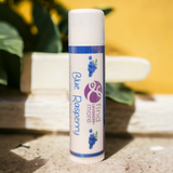 Lip balm tube labeled 'Blue Raspberry' with a blurred natural background