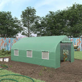 Green greenhouse in a garden with trees and a fence in the background