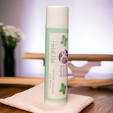 Lip balm tube with 'Herbal Mint' flavor on a wooden surface