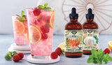 Two bottles of MYCO Extracts on a table with a glass of pink lemonade and raspberries.