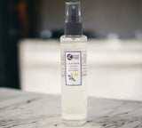 Clear spray bottle with lavender and lemon essential oil label on a marble surface.