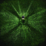 Top-down view of a person walking on grass with a light source creating a pattern