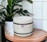 Vanilla Sexy Man body butter jar on a wooden surface with plants in the background