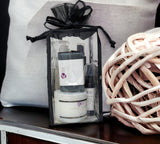 Clear gift bag with skincare products on a wooden surface next to a woven ball.
