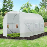 White greenhouse on a grassy area with trees in the background