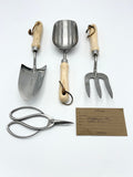 Set of gardening tools including a trowel, scoop, fork, and shears on a white background with a business card.