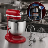 Red stand mixer with a stainless steel bowl on a kitchen counter, shown with two metal attachments and a circular inset explaining the motor technology.
