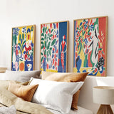 Modern Colorful Floral Matisse Wall Art Set on a wall above a bed with pillows and a lamp.