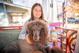 Person holding a dog and a jar of ROSEMARY MINT EXFOLIATING BODY WASH 16 oz. (with Arnica & Epsom Salt)