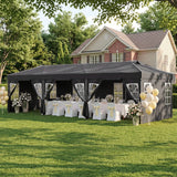 A large black event canopy tent is set up on a green lawn in front of a house, decorated with white tablecloths, white chairs with yellow bows, floral arrangements, and clusters of white and pale yellow balloons.