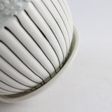 Close-up of a white ceramic bowl with black lines on a light gray background