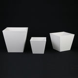 Three white square planters of different sizes on a black background