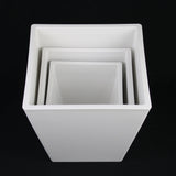 Set of white square planters of different sizes on a black background