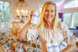 Woman holding multiple bottles of 'Good' brand products in a home setting.