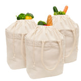 Three beige drawstring bags filled with vegetables on a white background