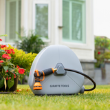 Giraffe Tools garden hose reel with hose on grass in front of a house