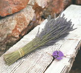 Bouquet of lavender on a stone surface with a purple flower in the foreground.