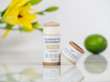 Aluminum-free deodorant stick with packaging on a reflective surface with flowers and a lime in the background.