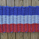 Doormat with red, white, and blue pattern on a wooden floor