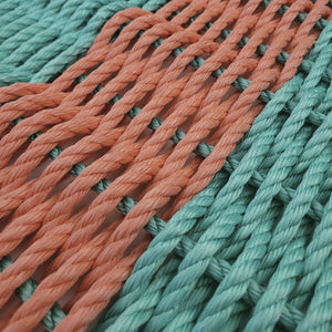 Close-up of interwoven teal and orange ropes on a white background