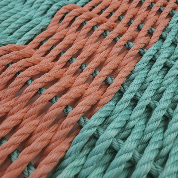 Close-up of interwoven teal and orange ropes on a white background