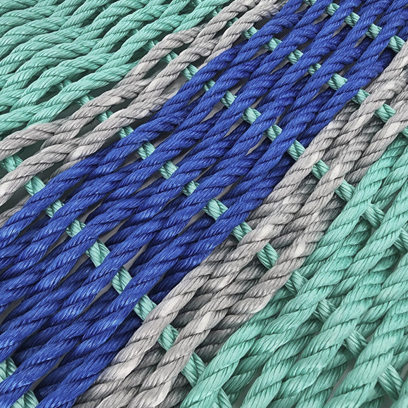 Close-up of braided ropes in blue, green, and gray on a light background