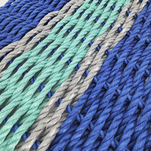 Close-up of braided ropes in blue, green, and gray on a light background