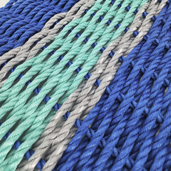 Close-up of braided ropes in blue, green, and gray on a light background