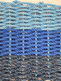 Close-up of woven blue and gray ropes with a beige background