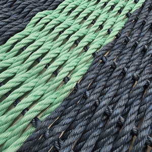 Close-up of green and black ropes woven together on a wooden surface