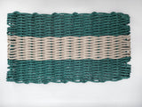 Woven mat with green and beige stripes on a white background