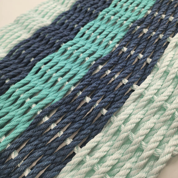 Close-up of woven fabric with blue and green stripes on a plain background