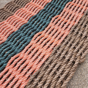 Close-up of a woven mat with multicolored ropes on a concrete surface
