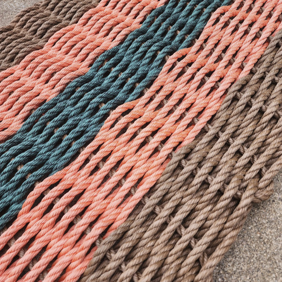 Close-up of a woven mat with multicolored ropes on a concrete surface