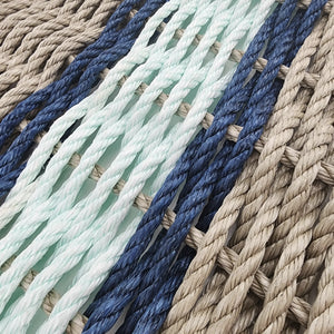 Stack of braided ropes in beige, green, and light blue on a white background