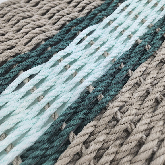Stack of braided ropes in beige, green, and light blue on a white background