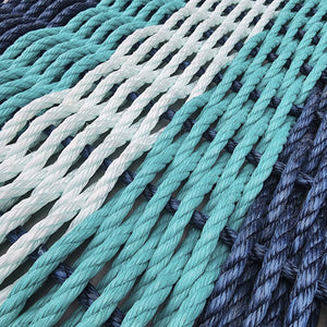Close-up of braided ropes in teal, white, and gray on a textured surface.