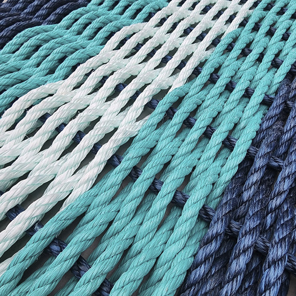 Close-up of braided ropes in teal, white, and gray on a textured surface.
