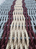 Close-up of braided ropes in beige, red, and gray on a textured surface.