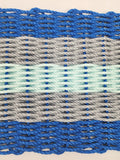 Close-up of woven fabric with blue, gray, and green pattern on a beige background