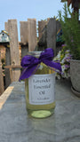 Bottle of lavender essential oil with a purple bow on a stone surface outdoors.