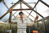 Person holding a metal frame inside a greenhouse