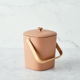 Astrik Compost Bin with wooden handle on a light marble background